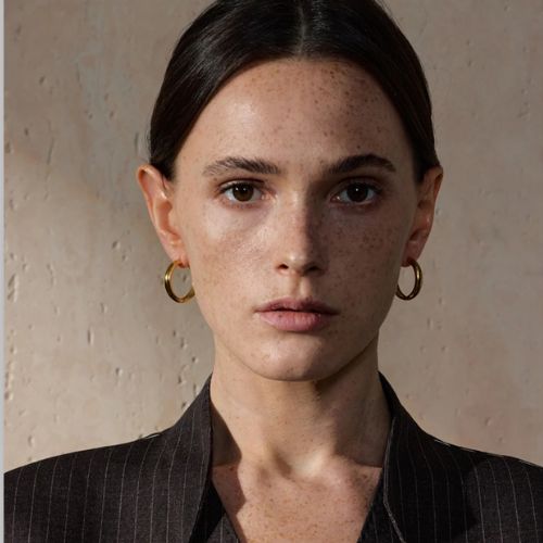 belle femme qui porte une belle boucle d'oreille dormeuse doré en acier inoxydable