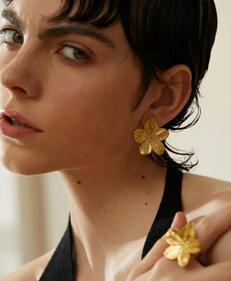 femme porte une boucle d'oreille fleur et bague fleur