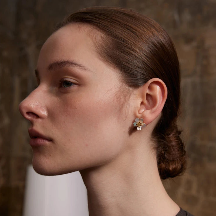 une femme prestigieuse porte une boucle d'oreille fleur